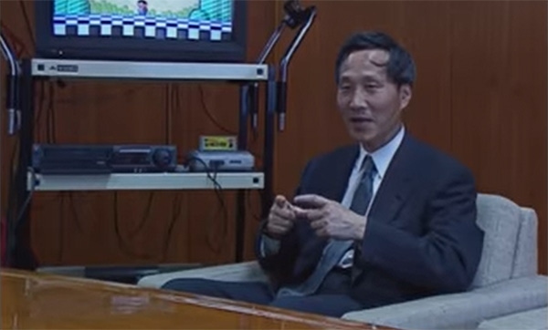 Masayuki Uemura sits in front of a TV explaining the SNES.