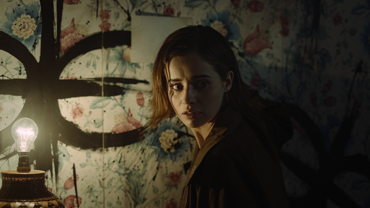 Erica explores a low-lit room with strange symbols on the walls Erica explores a low-lit room with strange symbols on the walls