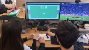A pair of people playing a pong-like soccer game using a unique sliding, twisting controller