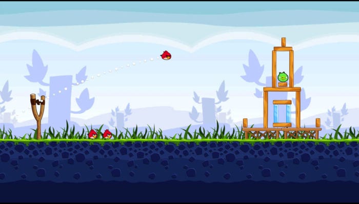 An Angry Birds Screenshot where a giant slingshot flings a red, spherical bird into a tower of wooden and glass blocks.