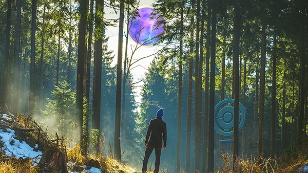 Pokemon Go's season of mischief promo image. A trainer looks up at a purple orb while standing near a Pokestop in the woods.