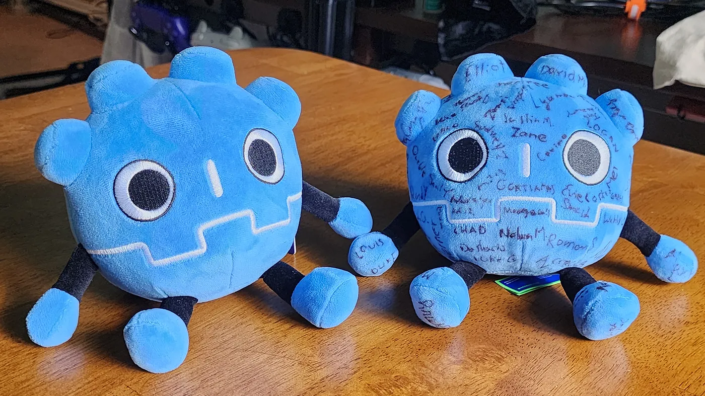 Two plush Godot mascots. One has a number of names sharpied on it. Two plush Godot mascots. One has a number of names sharpied on it.