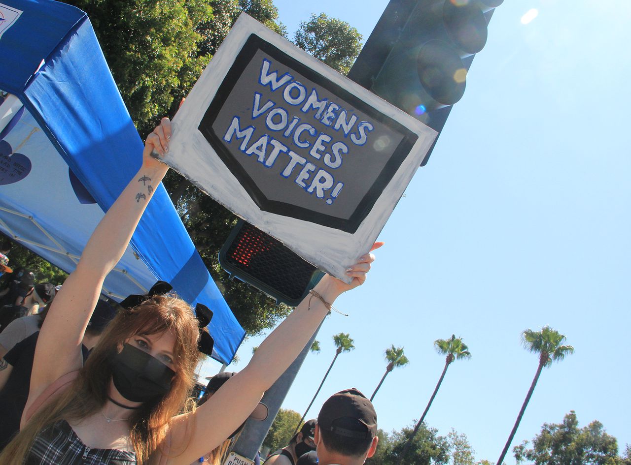 A woman holds a sign saying A woman holds a sign saying