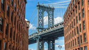 A photo of the Brooklyn Bridge between old brownstone buildings. A photo of the Brooklyn Bridge between old brownstone buildings.