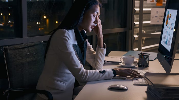 A tired woman works in an unlit office at night. A tired woman works in an unlit office at night.