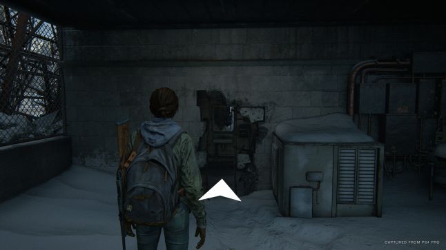 The player in front of a large hole in the wall, with a navigation assistance arrow pointing towards it