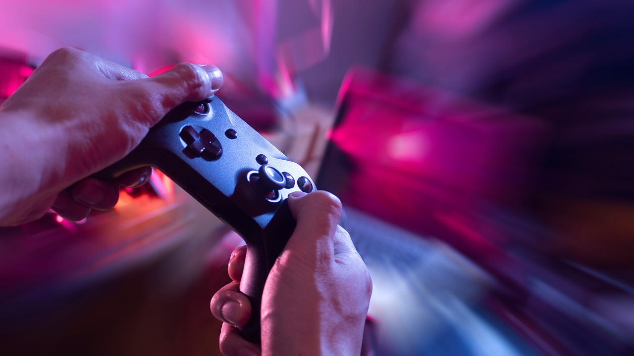 A person holds an Xbox controller as zoom effects blur the background. A person holds an Xbox controller as zoom effects blur the background.