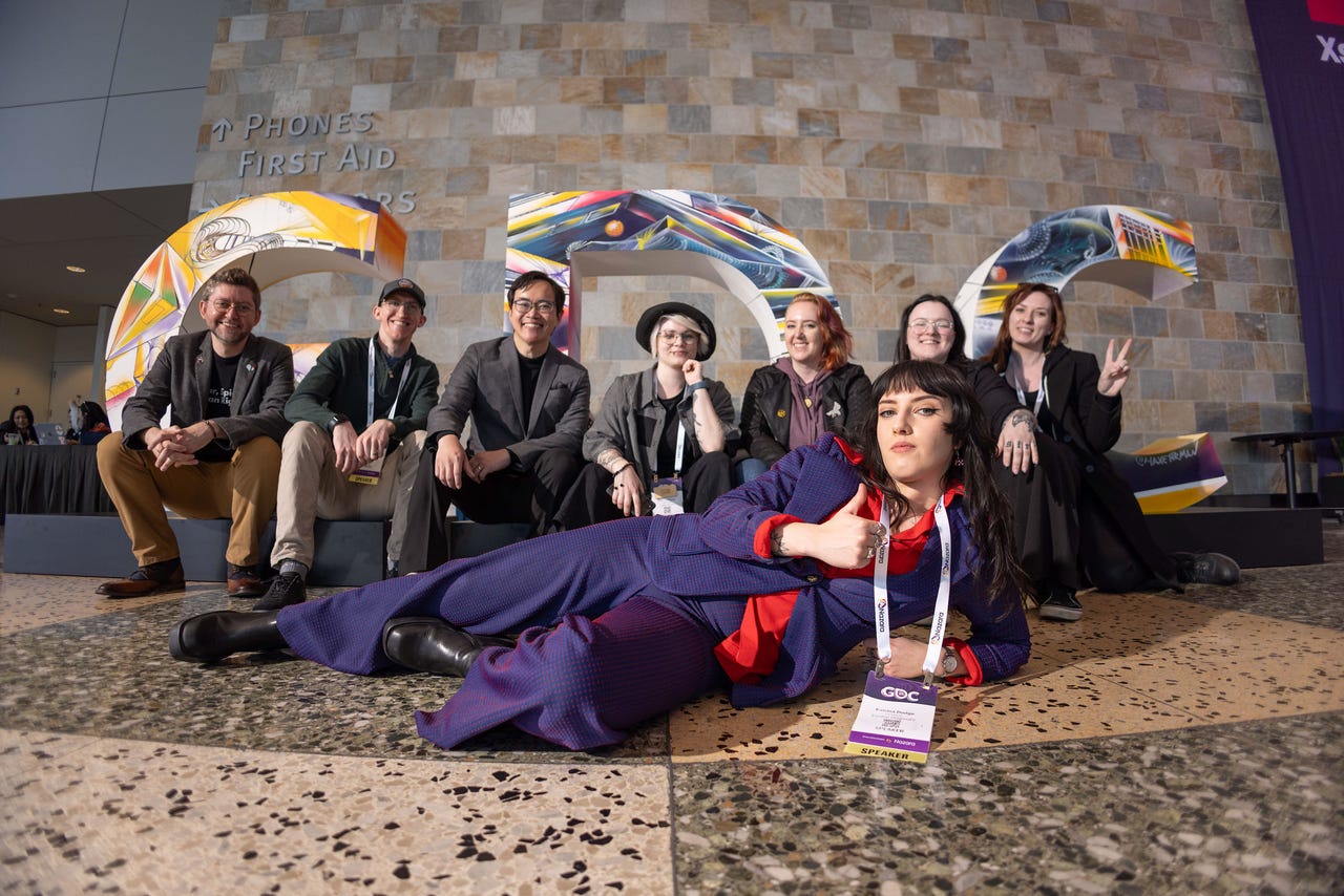 A group of people pose in front of the GDC logo, with one woman in a blue suit sitting in front of the others. A group of people pose in front of the GDC logo, with one woman in a blue suit sitting in front of the others.