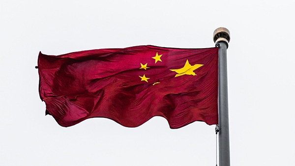 The Chinese flag flies against a grey sky