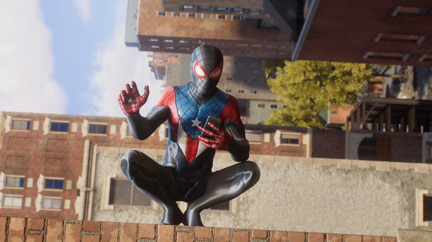 Miles Morales as Spider-Man looks at his phone while standing on a building sideways.
