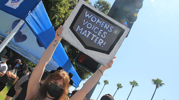 A woman holds a sign saying 