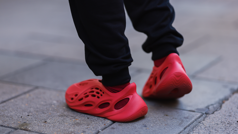 A fashion week guest seen wearing red adidas Yeezy shoes, outside paul and joe during London Fashion Week September 2022.