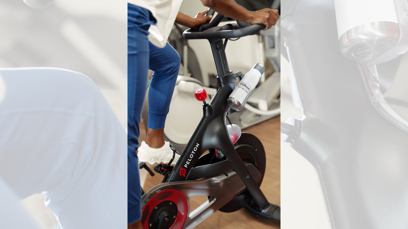 A Hilton guest working out on Peloton equipment with a Hilton-branded water bottle.