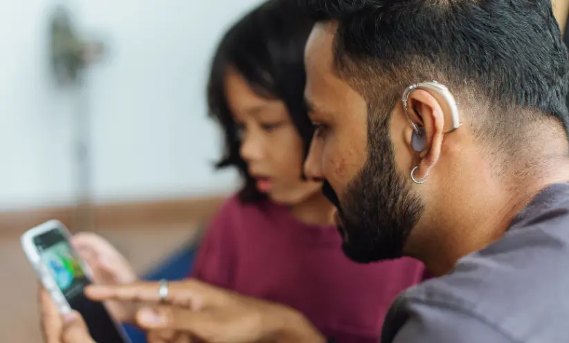 Mann verbindet sein Hörgerät mit seinem Handy mittels Bluetooth.webp