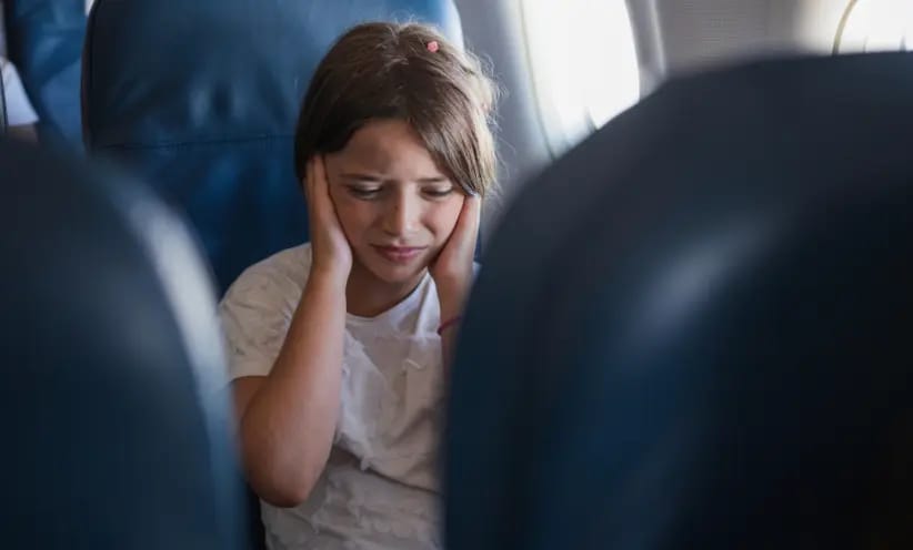 kind-haelt-sich-im-flugzeug-die-ohren-zu-desktop.webp