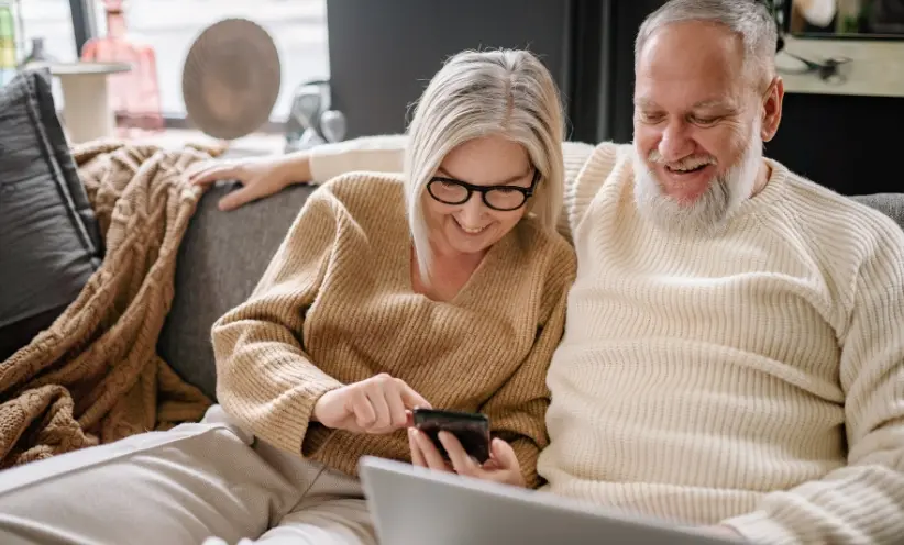 geers-hörgeräte-paar-lachend-computer-laptop-smartphone.webp