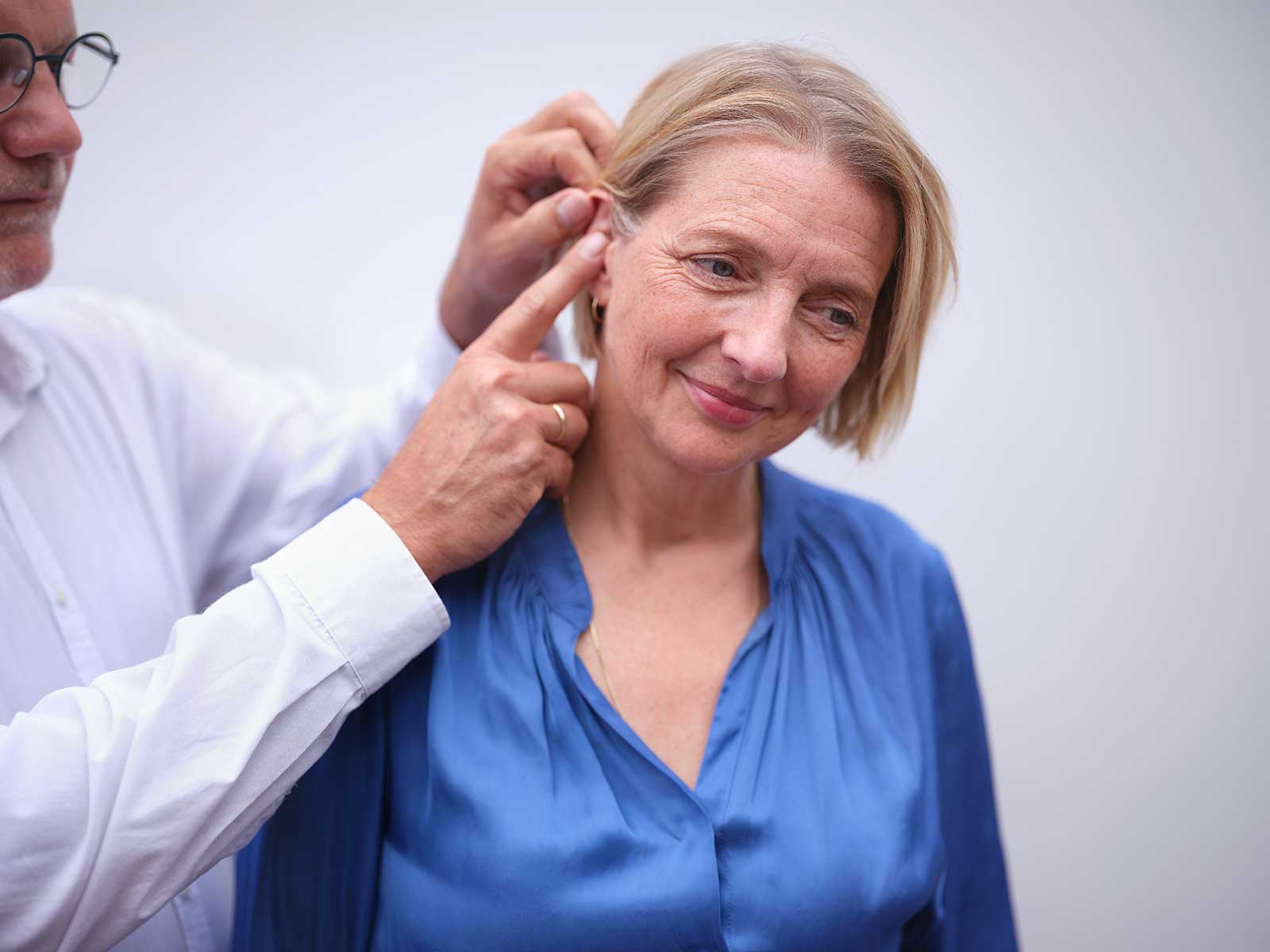eon-woman-blue-shirt-getting-hearing-aid-fitted.jpg