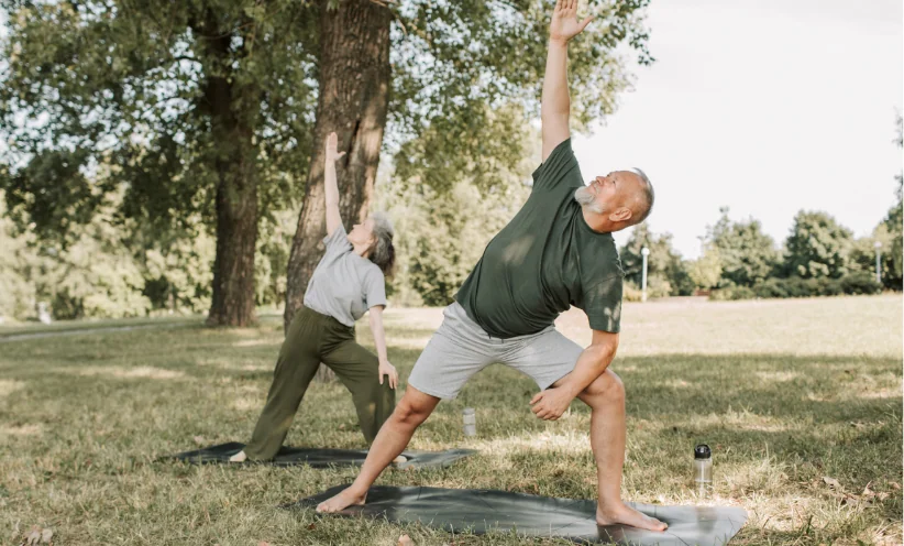Ein Mann und eine Frau machen gemeinsam Yoga auf einer Wiese