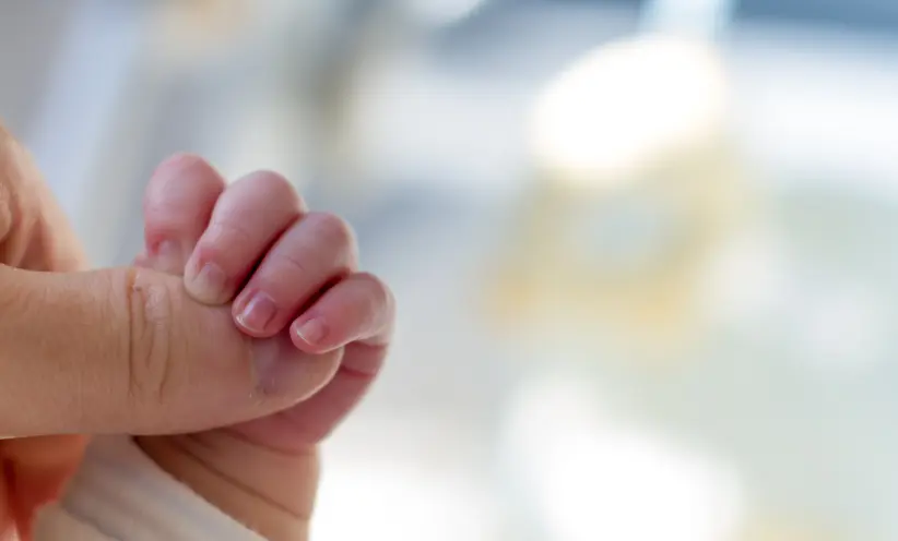 baby-umgreift-mit-seiner-kleinen-hand-den-daumen-eines-erwachsenen.webp