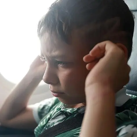 kleiner-junge-haelt-sich-ohren-zu-im-flugzeug.webp