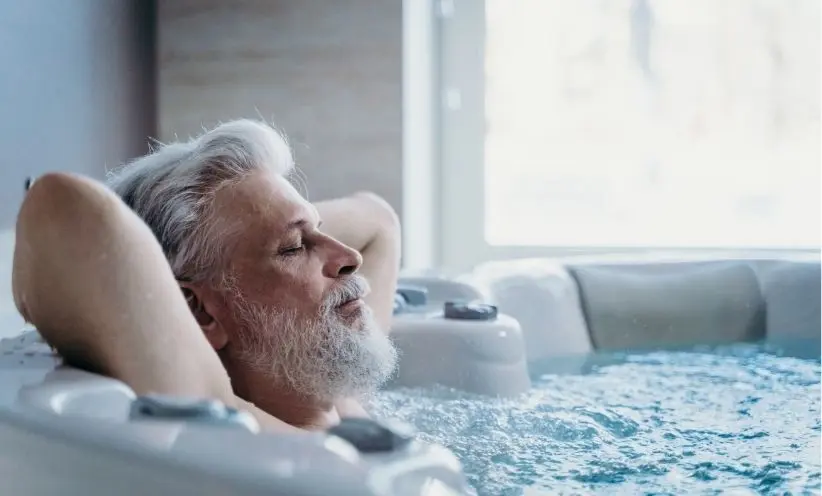 Mann im mittleren Alter liegt mit geschlossenen Augen im Whirlpool und genießt die Ruhe. Entspannung fällt bei Tinnitus oft schwer.