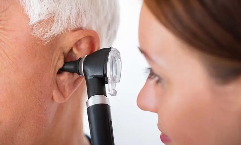 eine-hno-aerztin-untersucht-das-ohr-bei-einem-grauhaarigen-mann-mit-einem-schwarzen-otoskop.
