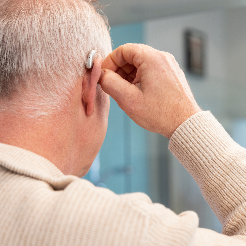 Elderly-man-putting-on-hearing-aid.png