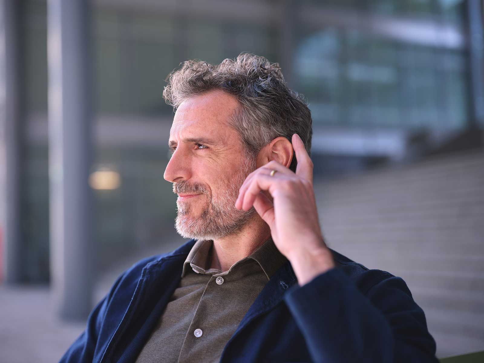 man-tapping-eon-hearing-aid-sitting.jpg
