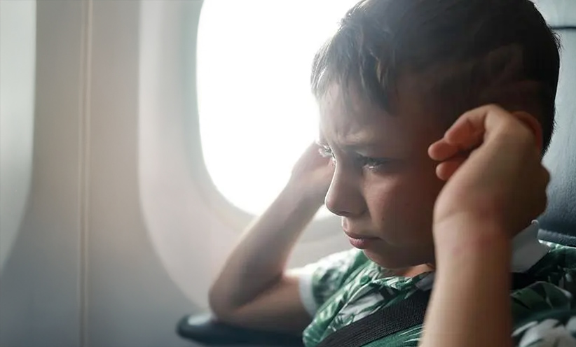 kleiner-junge-haelt-sich-ohren-zu-im-flugzeug.jpg