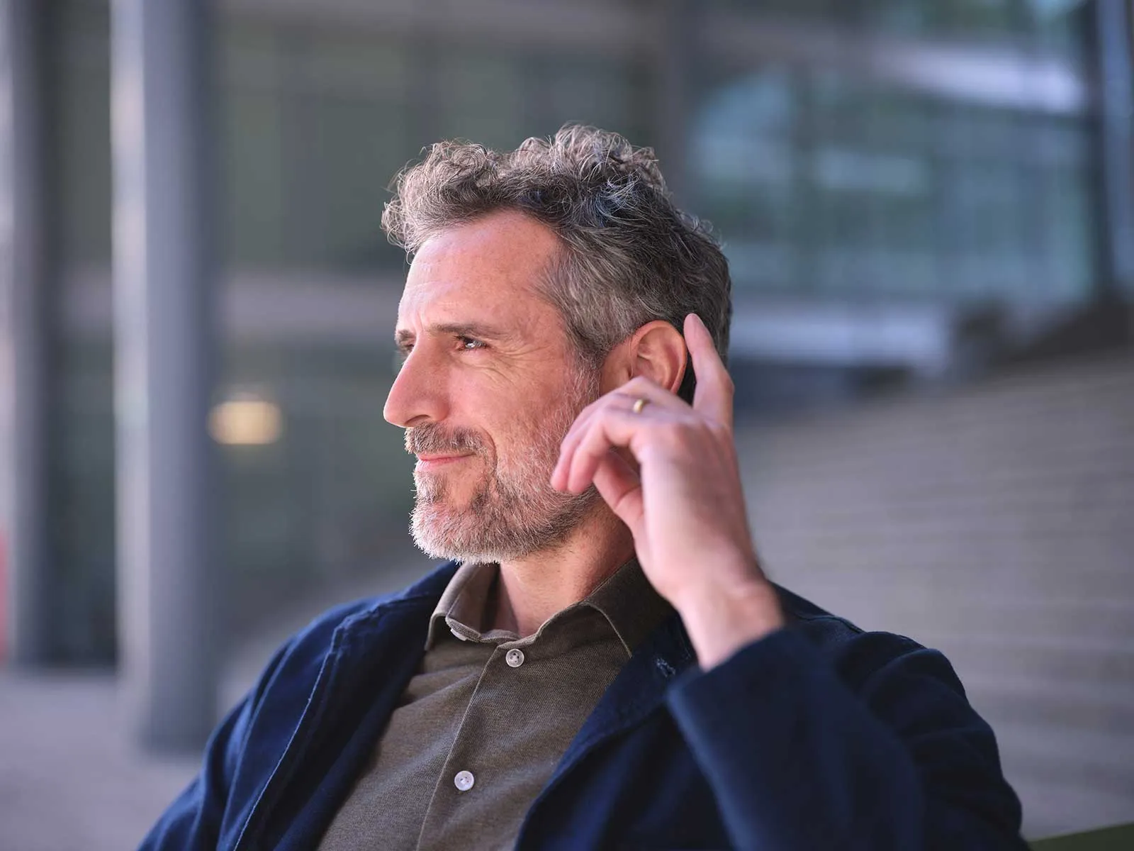 man-tapping-eon-hearing-aid-sitting (1).webp