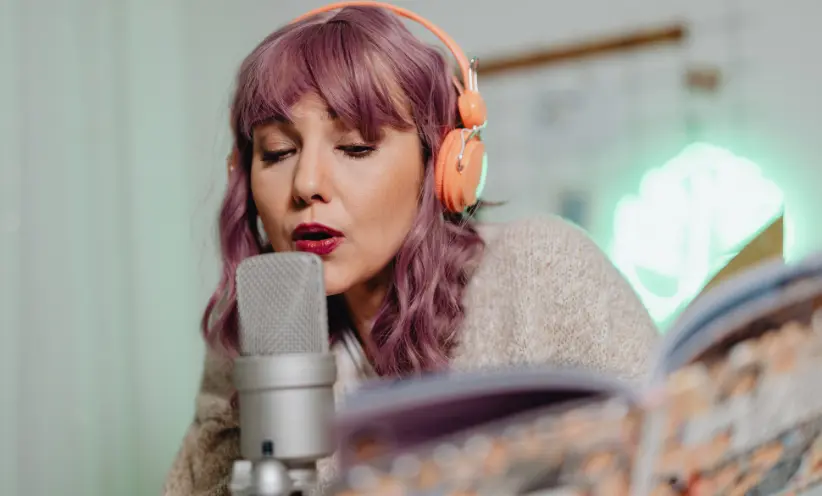 Frau trägt Kopfhörer und singt in das Mikrofon.webp