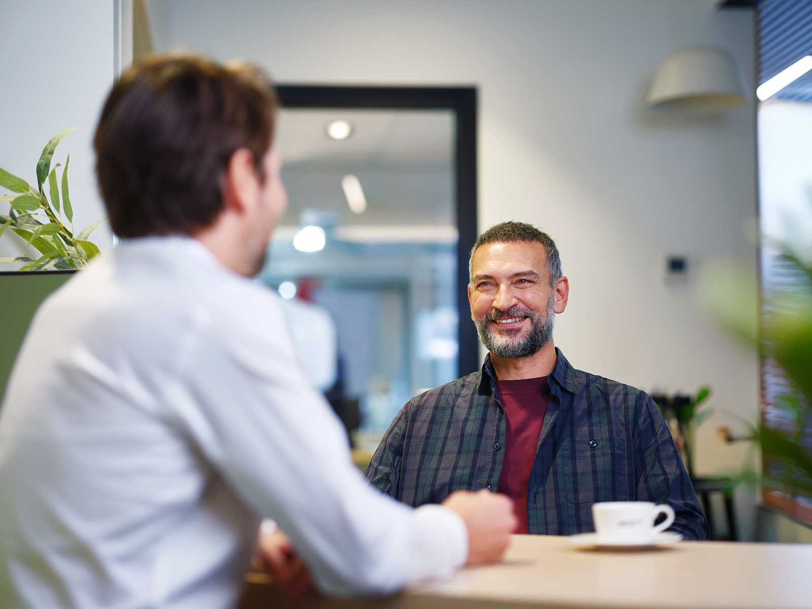 man-audicien-aan-tafel-lachend-blauw-shirt.jpg