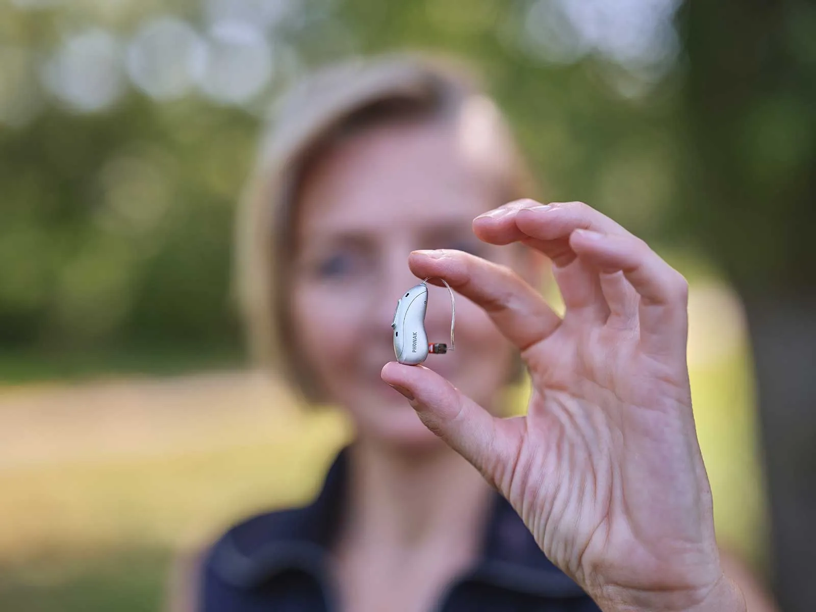 eon-close-up-hearing-aid-held-fingers.webp