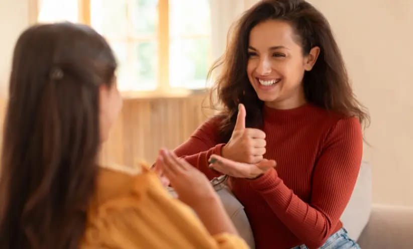Eine Frau spricht mit Gebärdensprache zu einer anderen Frau_Desktop.webp