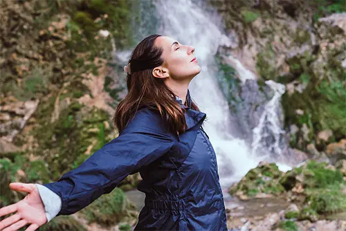 frau-in-natur-vor-wasserfall.webp