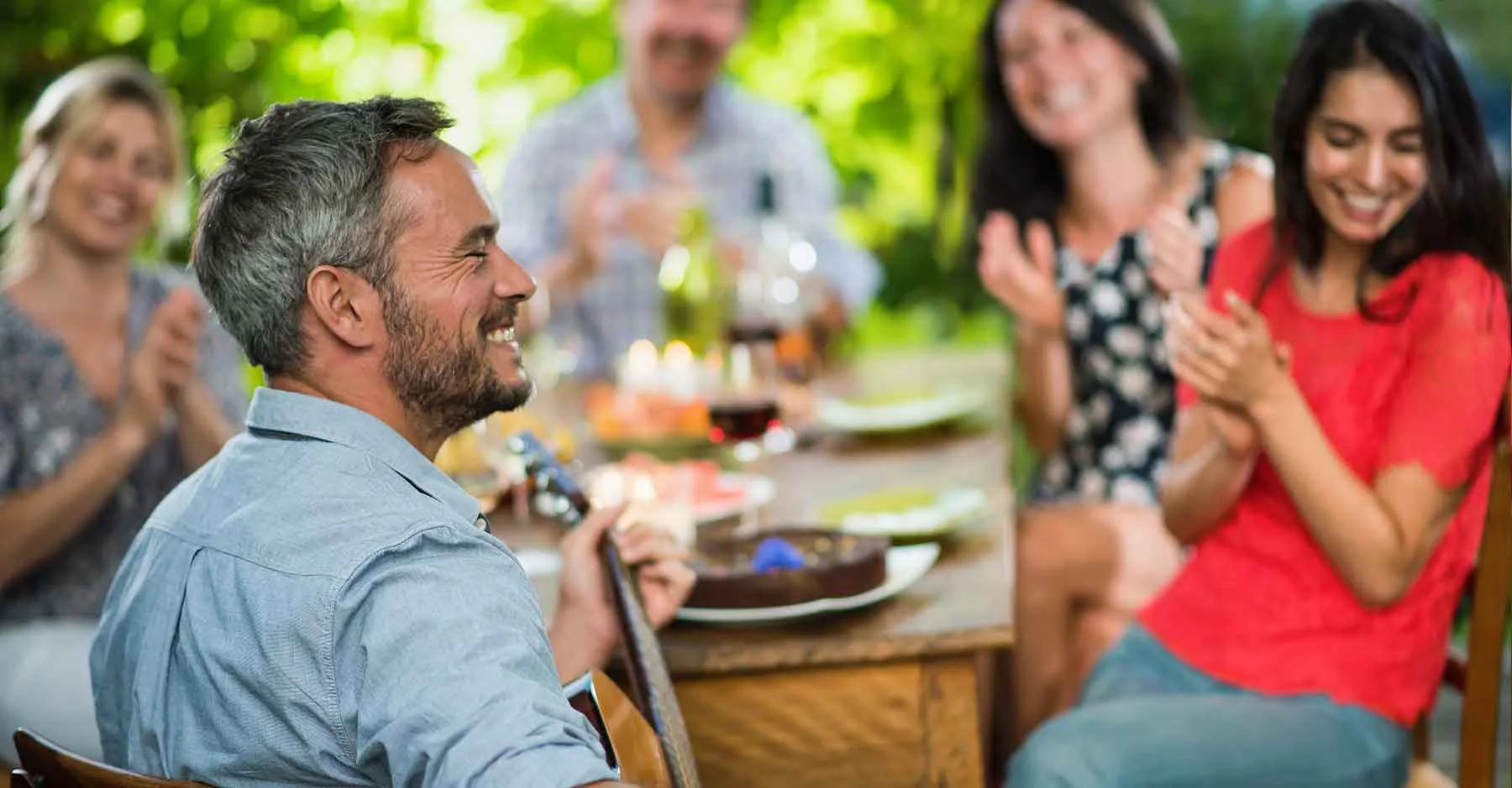 man-speelt-gitar-aan-een-tafel-met-mensen.jpg