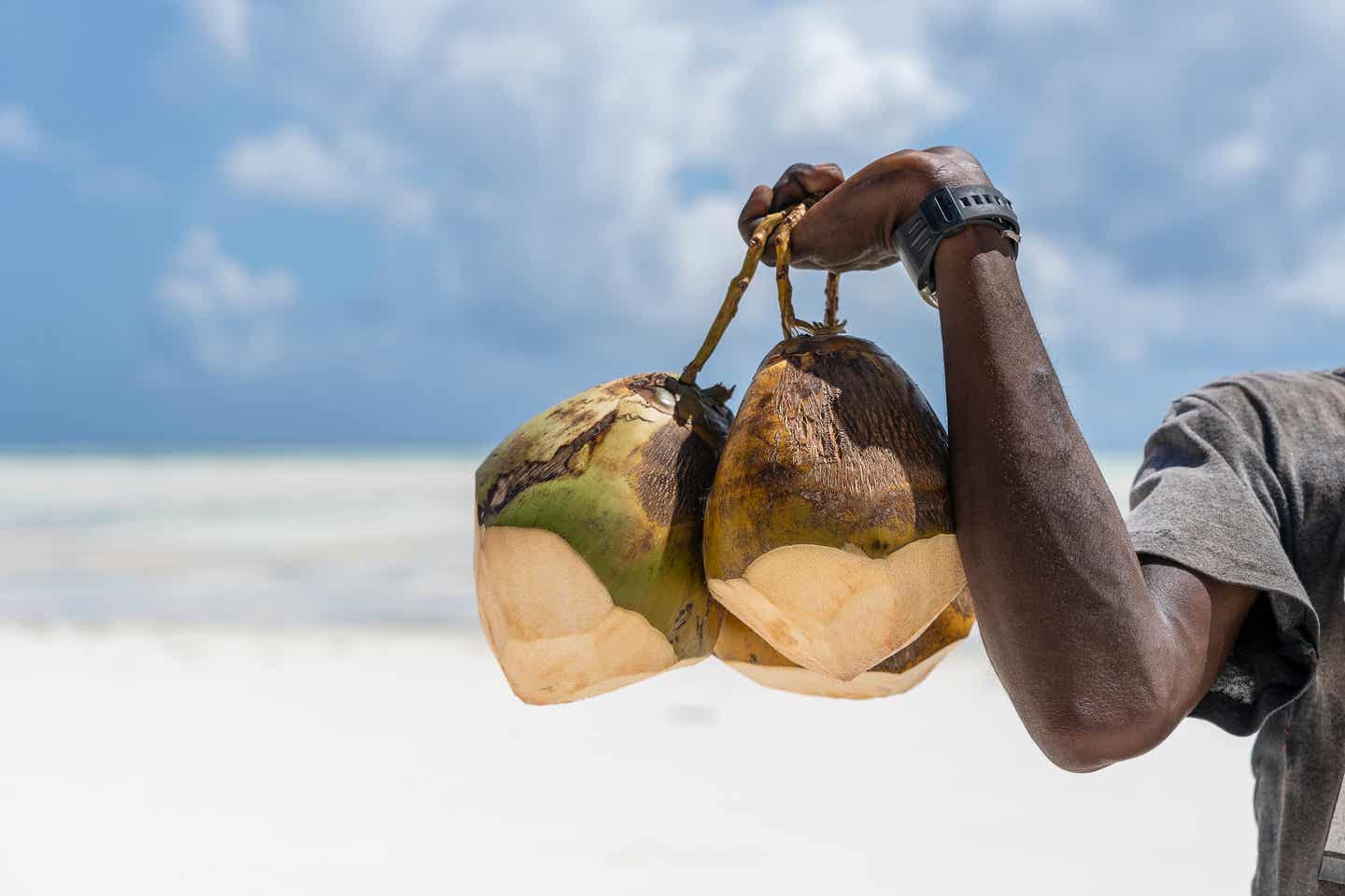 Sansibar Essen: Mann verkauft Kokosnüsse am Sandstrand