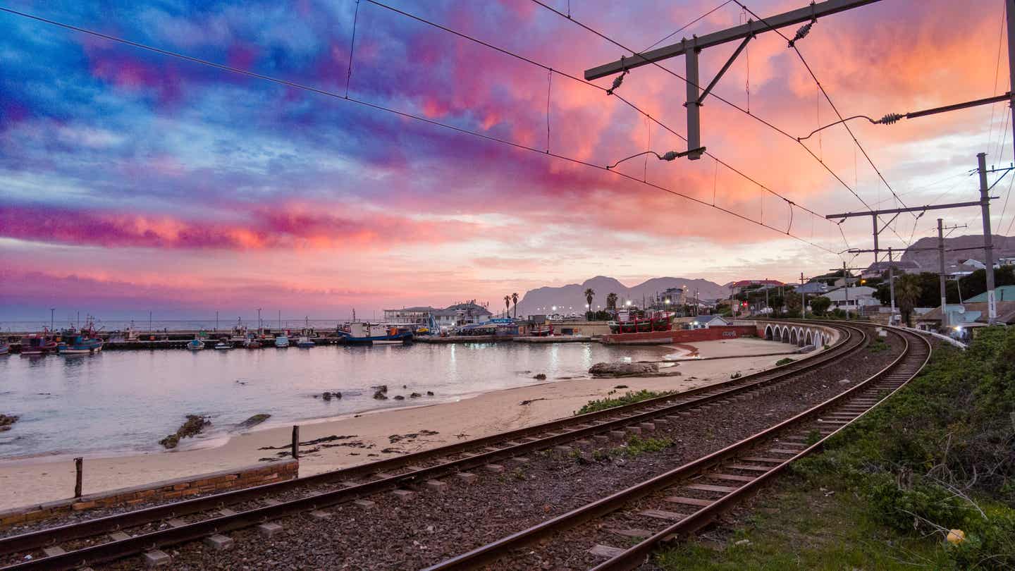Südafrika Urlaub: Bahnlinie am Meer mit spektakulärem Sonnenuntergang