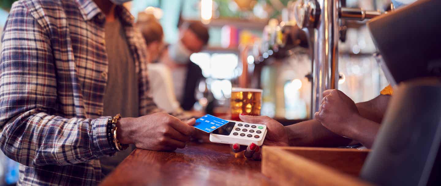 Währungen der Karibik: Mann bezahlt in einer Bar