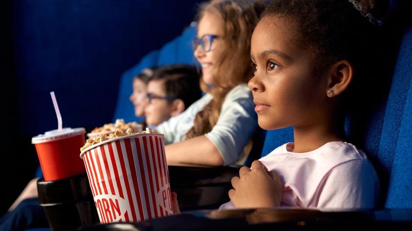 Kids eating popcorn in the theater, SerhiiBobyk, iStock / Getty Images Plus