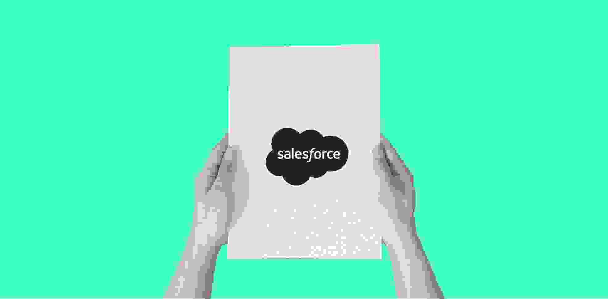hands holding a sheet of paper with a word salesforce, on a green background