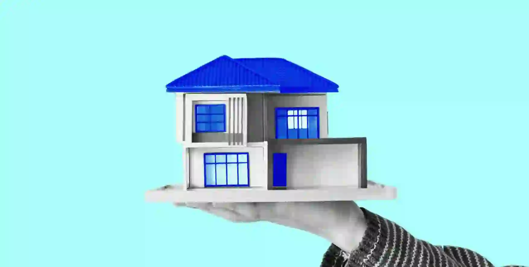 a person holding a house model on his hand