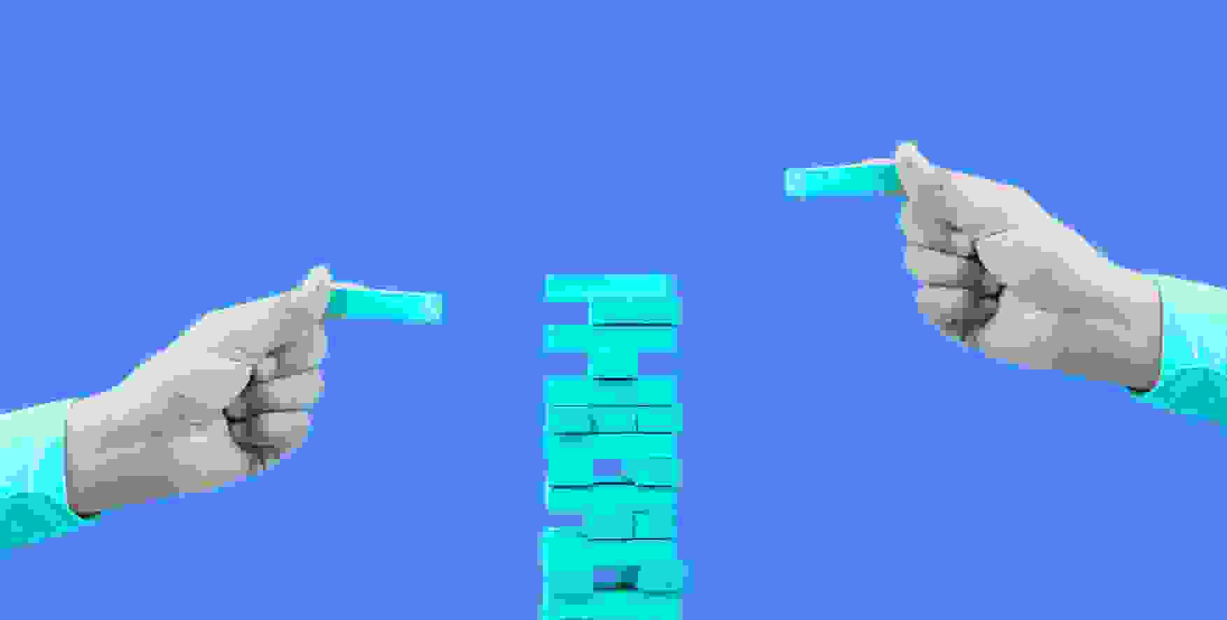 two hands building jenga on blue background