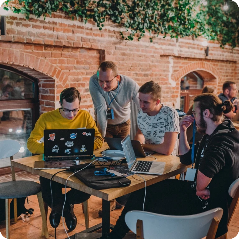 A diverse group of individuals sitting around a table, engrossed in their work on laptops.