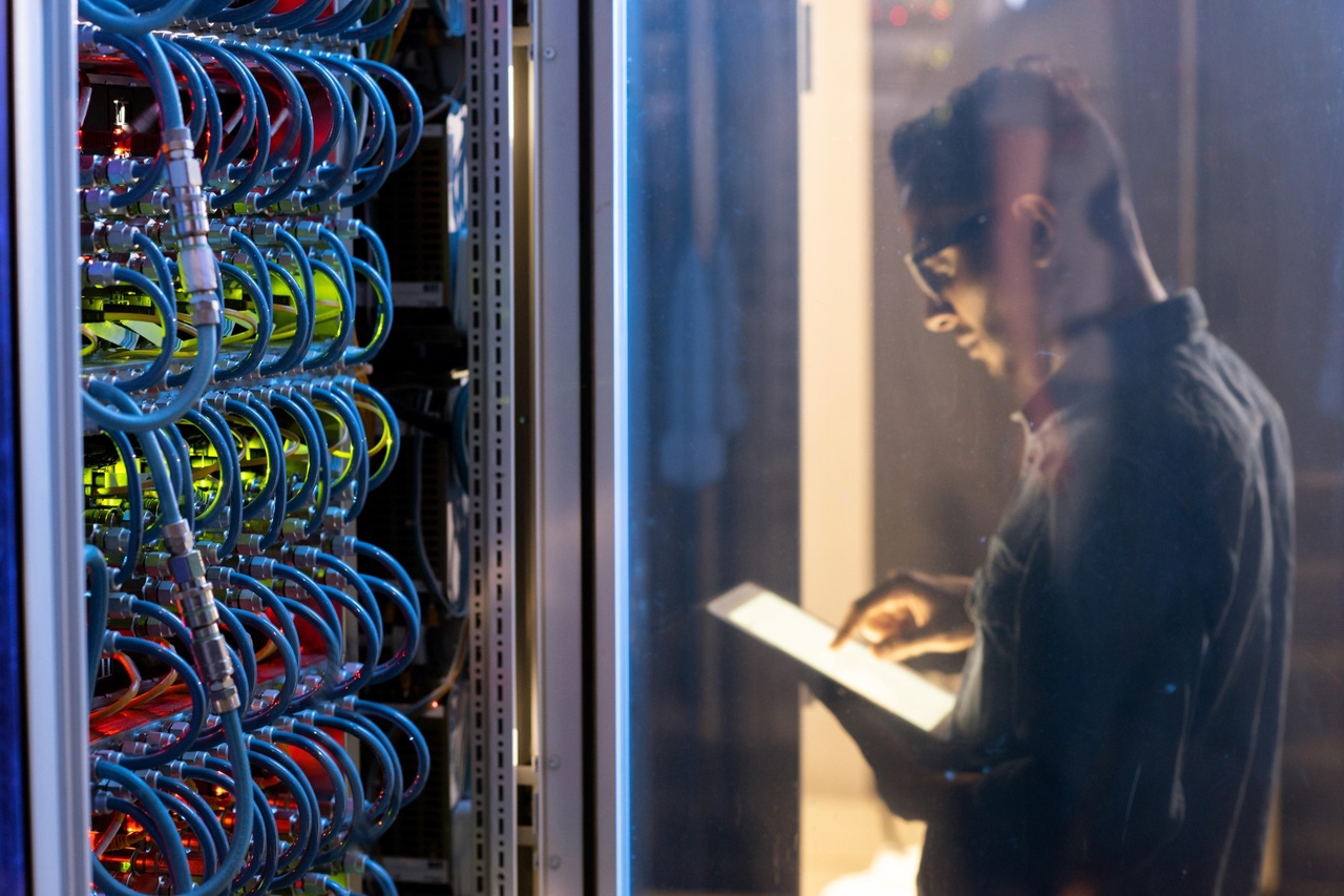 man checking a data center server on his tablet man checking a data center server on his tablet