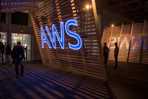Image of AWS logo on wooden slat background as people walk by.