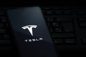 Tesla logo on smartphone screen laying on computer keyboard
