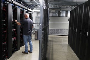 A staff member works among the racks and network switches in the data center of LightEdge Solutions in Altoona, Iowa.