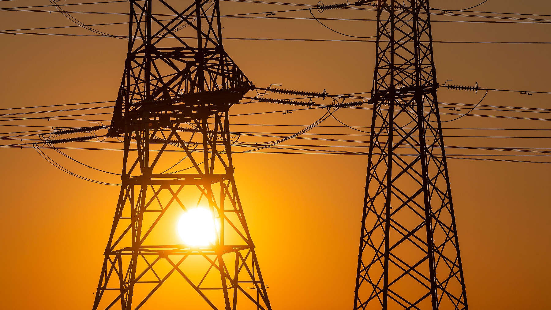 High voltage wires at a transmission tower at sunset