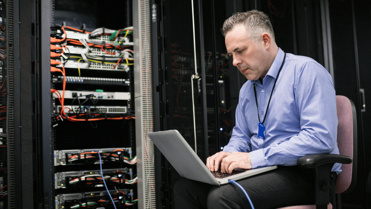 technician working on laptop in data center